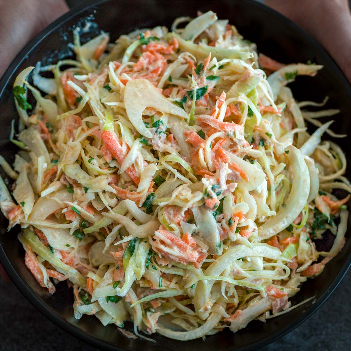 Creamy tuna cabbage salad in a black bowl, made with shredded cabbage, carrots, onion, and herbs in a light yogurt-style dressing. 