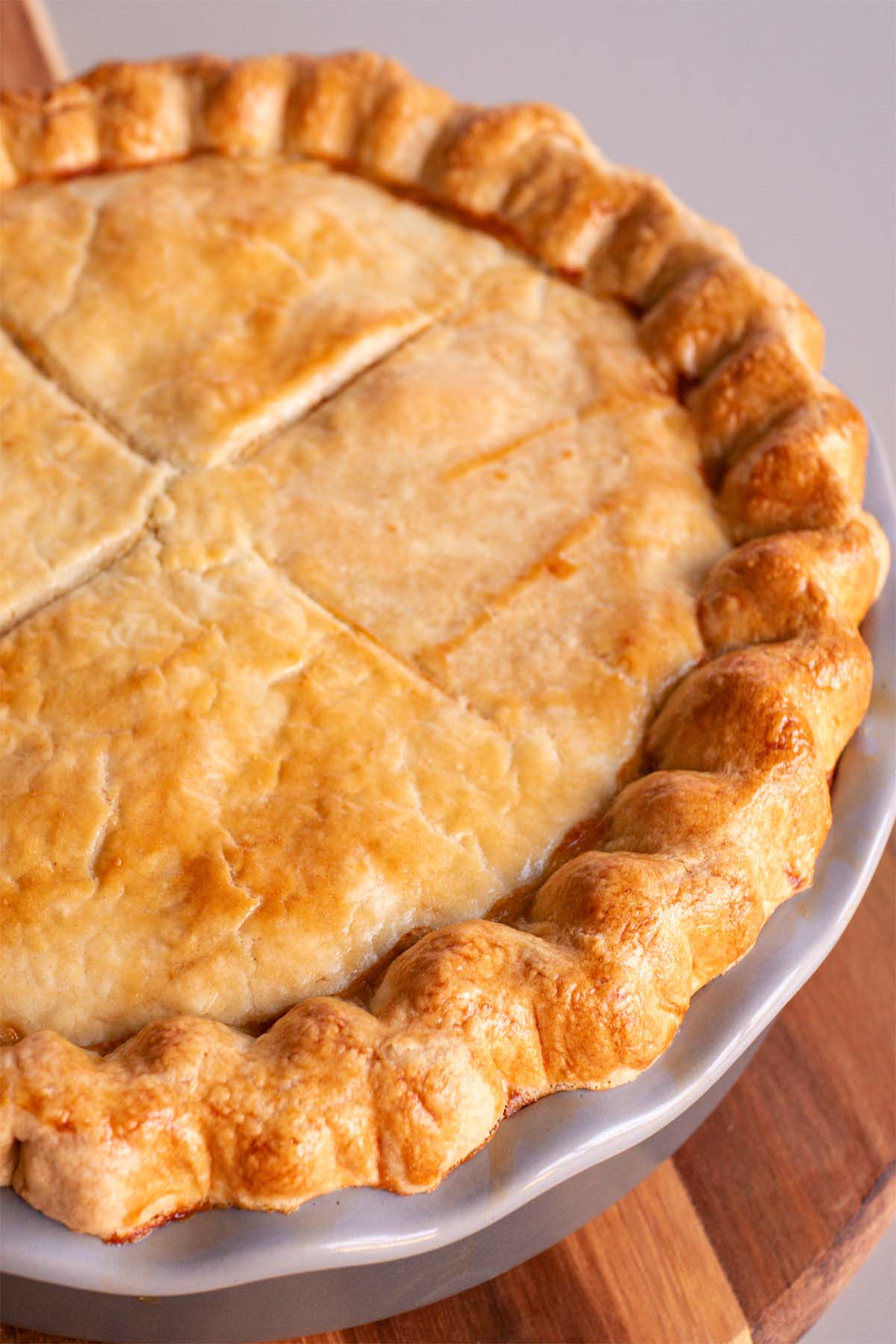Easy chicken pot pie with golden, flaky pie crust baked in a round pie dish, shown whole and ready to slice for serving. 