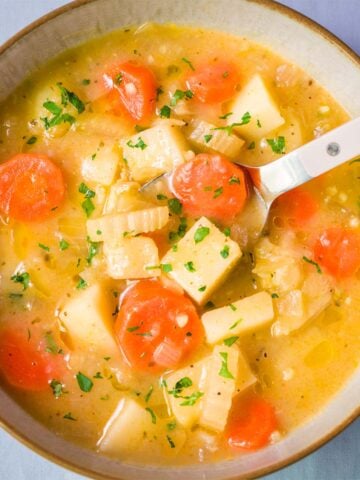 Bowl of easy carrot potato soup with tender potato chunks, sliced carrots, celery, and fresh parsley in a light broth.