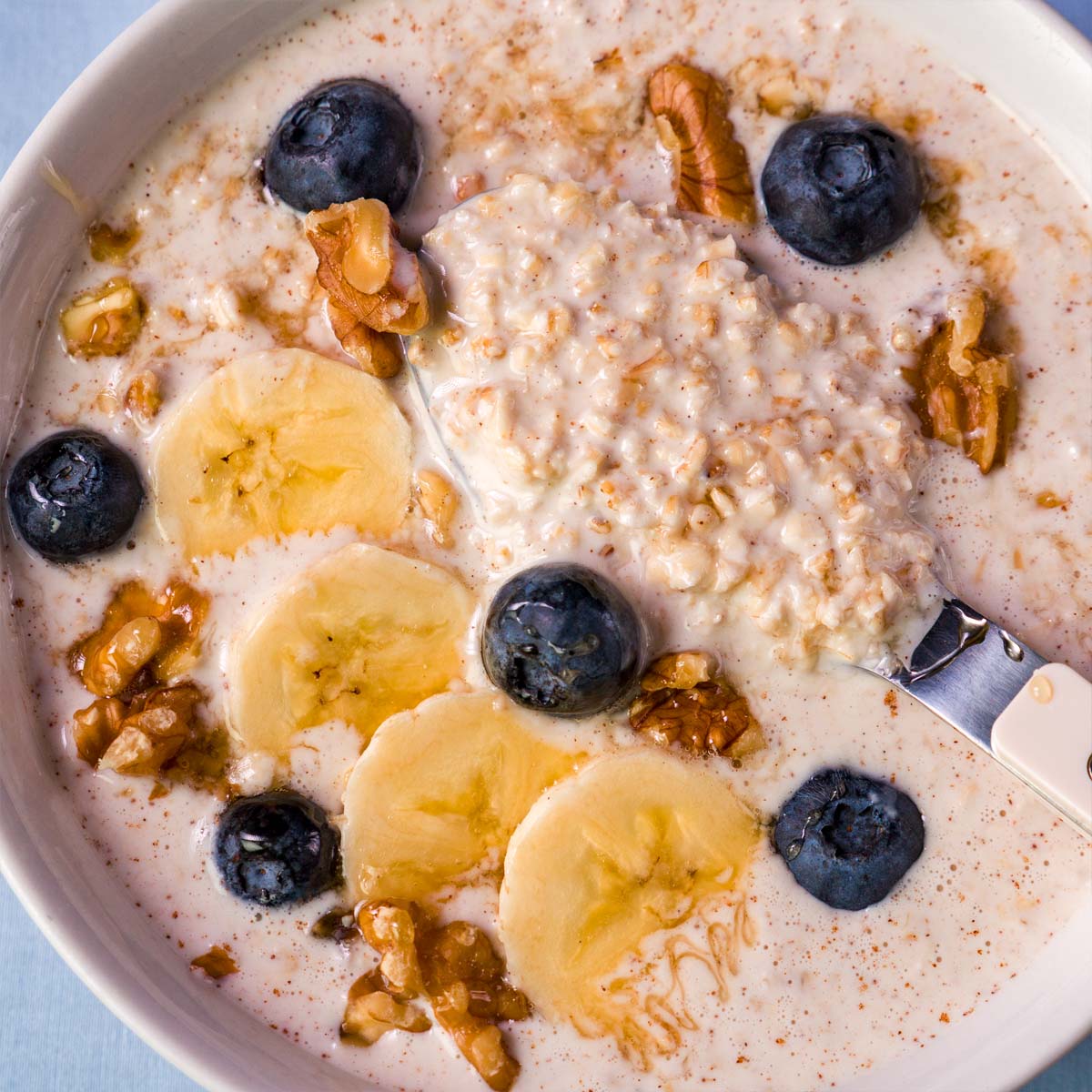 Close-up of overnight oats with Greek yogurt topped with banana slices, blueberries, and chopped walnuts.