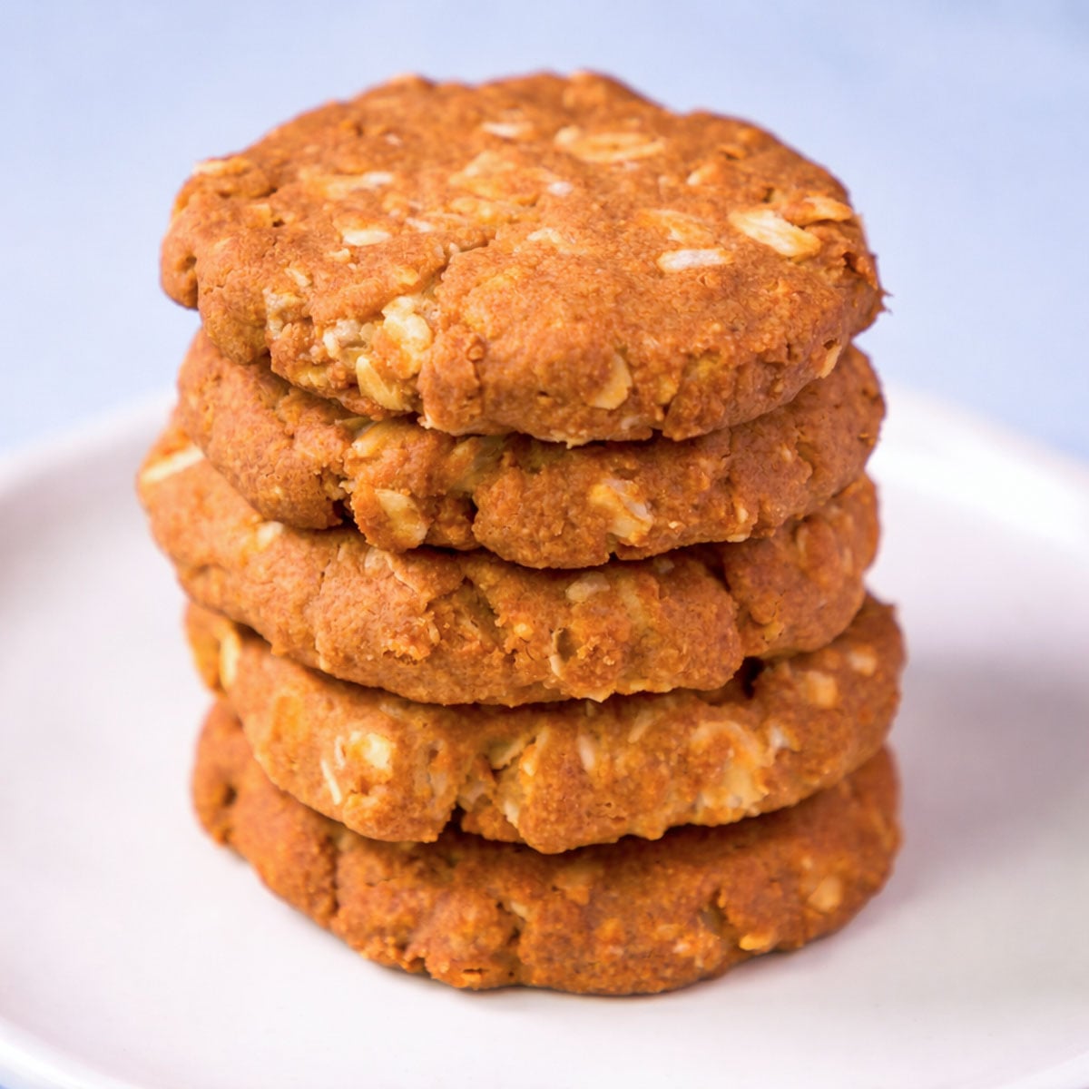 stack of 3 ingredient peanut butter oatmeal cookies on a white plate, thick and golden brown