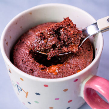 Chocolate lava mug cake in a polka-dot mug with a spoon lifting a gooey, molten chocolate bite.