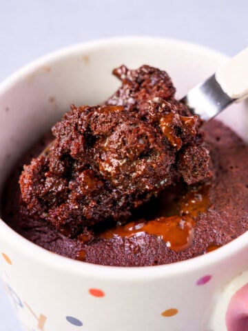 Spoonful of gooey chocolate lava mug cake lifted from a polka-dot mug, showing the molten chocolate center.
