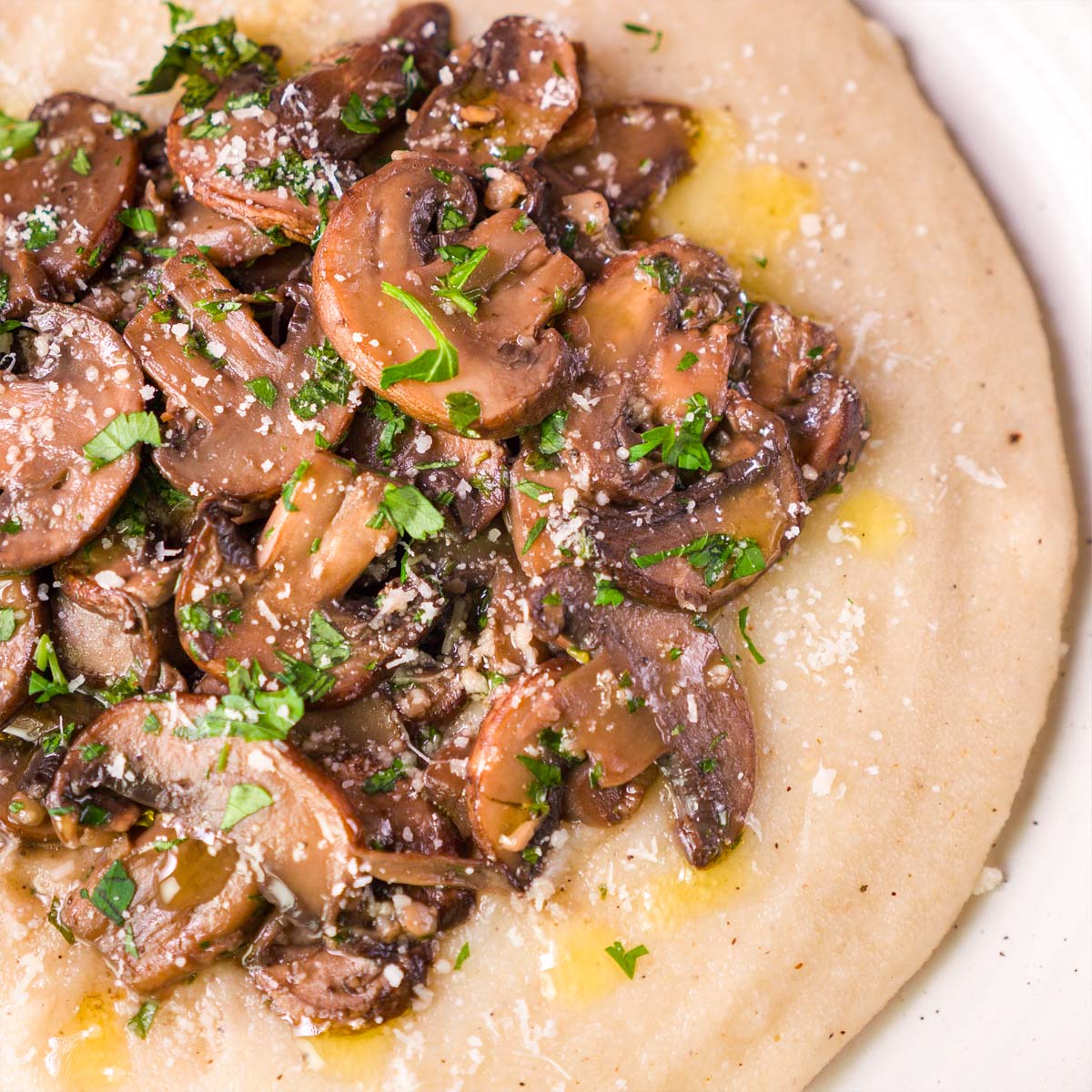 Close-up of creamy Parmesan polenta with sautéed cremini mushrooms, garlic, parsley, and a drizzle of olive oil