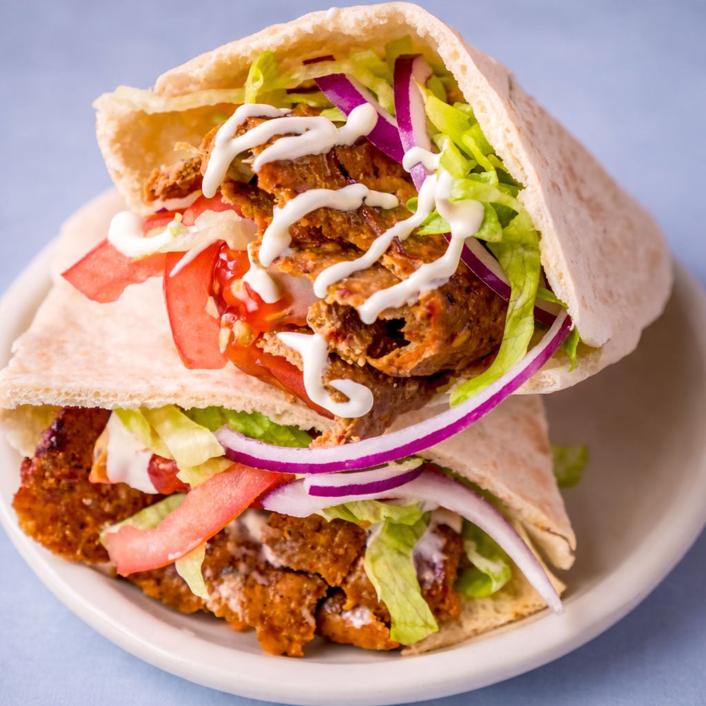 Viral doner kebab pita stuffed with sliced doner meat, lettuce, tomato, red onion, and creamy sauce