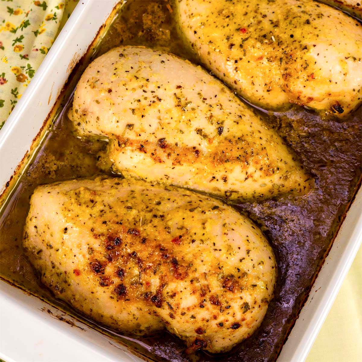 Baked chicken breasts in a casserole dish with golden seasoning and pan juices. a 2 ingredient high protein chicken dinner.