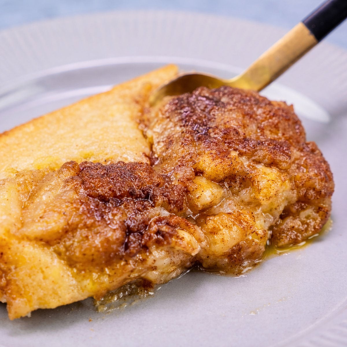 applesauce cobbler slice on a plate with a spoon showing soft apple filling and golden caramelized topping