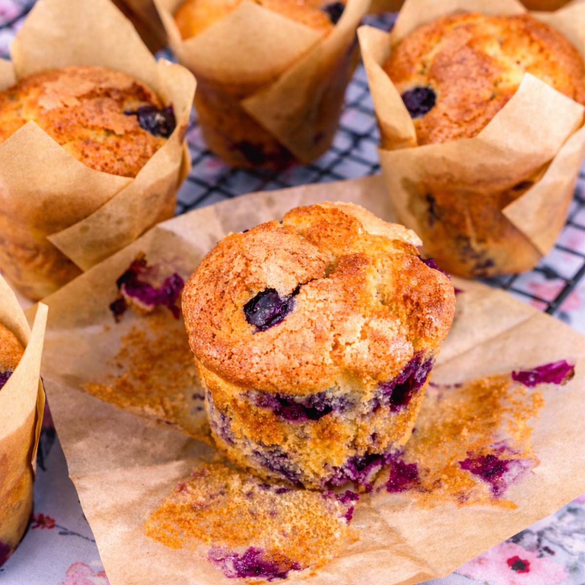 Homemade easy blueberry muffins with golden sugar tops and juicy blueberries, bakery-style blueberry muffins on parchment paper.