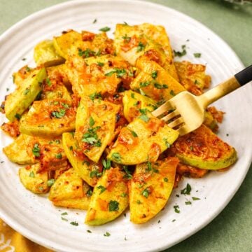 Sautéed Chayote Squash with caramelized onions and fresh parsley, served golden and tender on a white plate