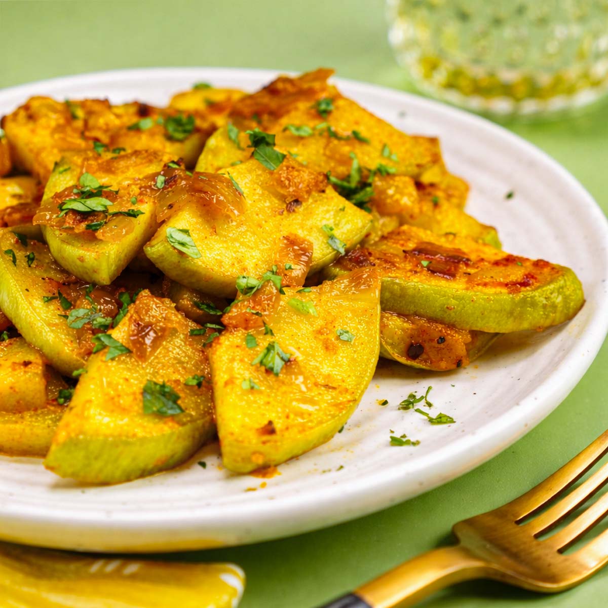 Sautéed Chayote Squash with caramelized onions, golden edges, and fresh parsley, served on a white plate