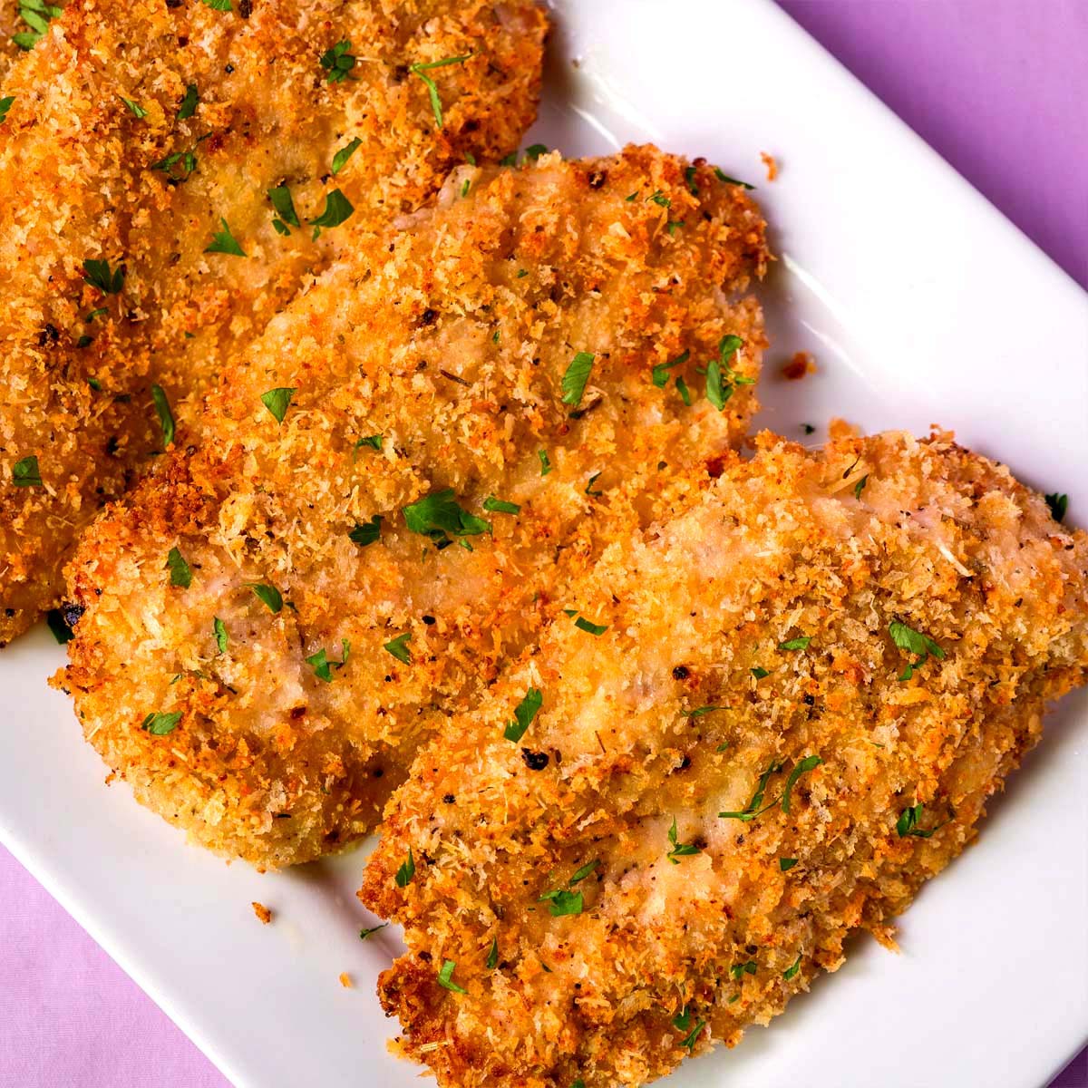 crispy baked chicken cutlets with parmesan breadcrumb coating served on a white platter