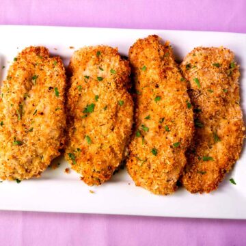 crispy baked chicken cutlets with parmesan and breadcrumbs served on a white platter