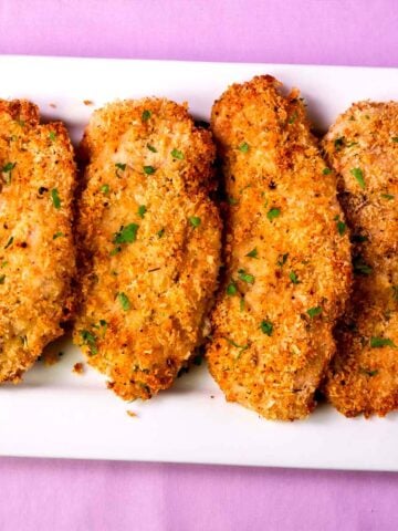 crispy baked chicken cutlets with parmesan and breadcrumbs served on a white platter