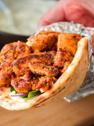 Greek chicken gyros wrap with grilled marinated chicken, fresh vegetables, and creamy tzatziki sauce in warm flatbread