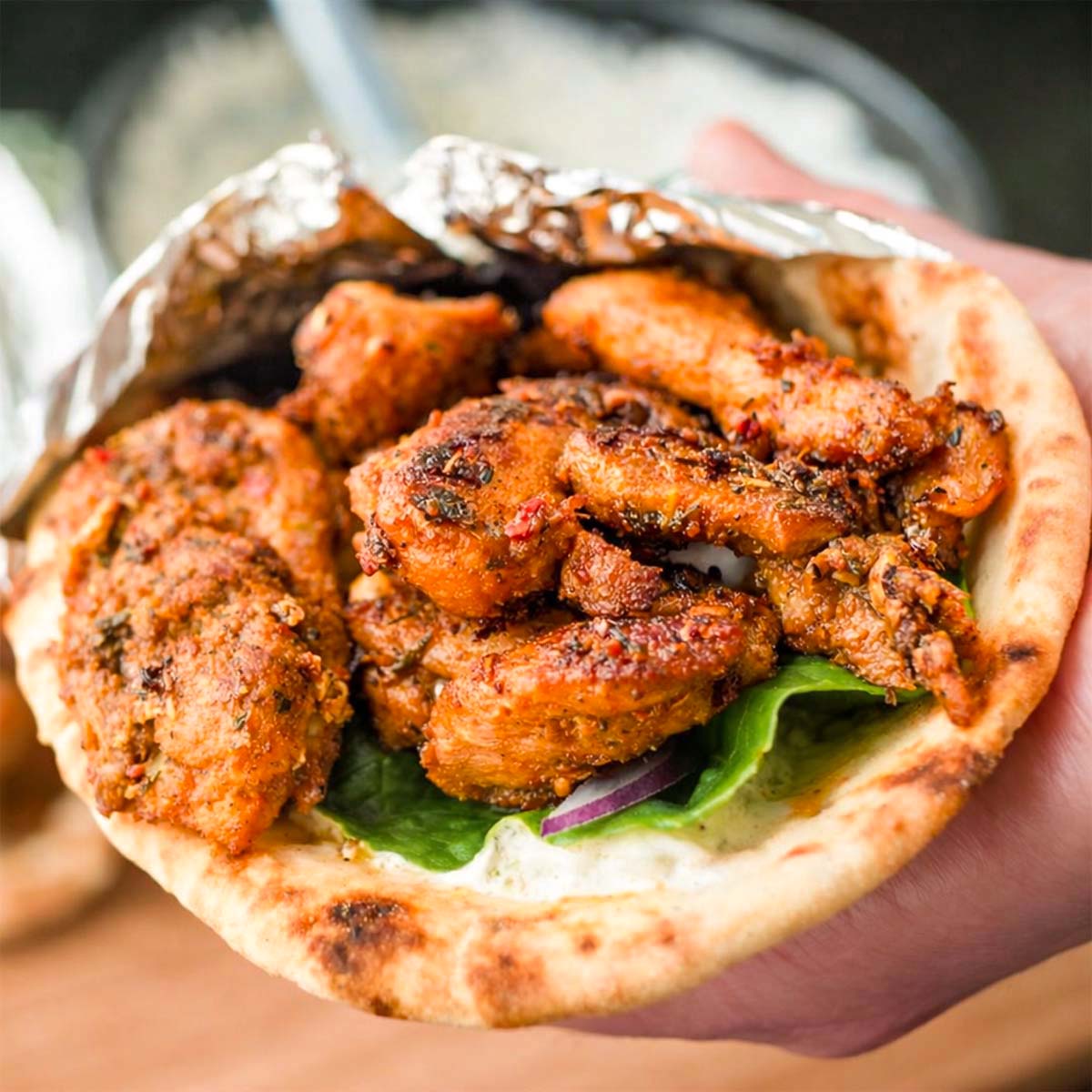 Greek chicken gyros with tzatziki wrapped in warm pita bread filled with grilled marinated chicken, lettuce, and onion