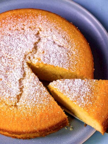 Slice of moist lemon olive oil cake dusted with powdered sugar on a plate