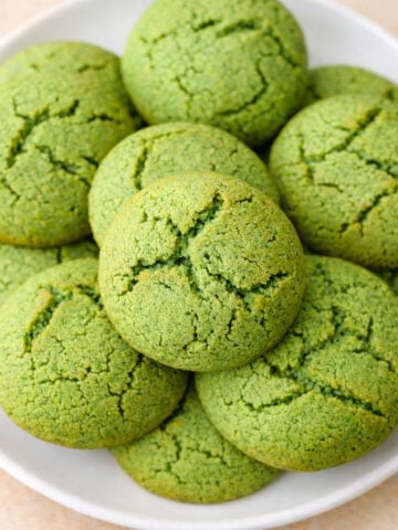 Fresh mint cookies with cracked tops stacked on a white plate, soft green mint biscuits baked until lightly golden