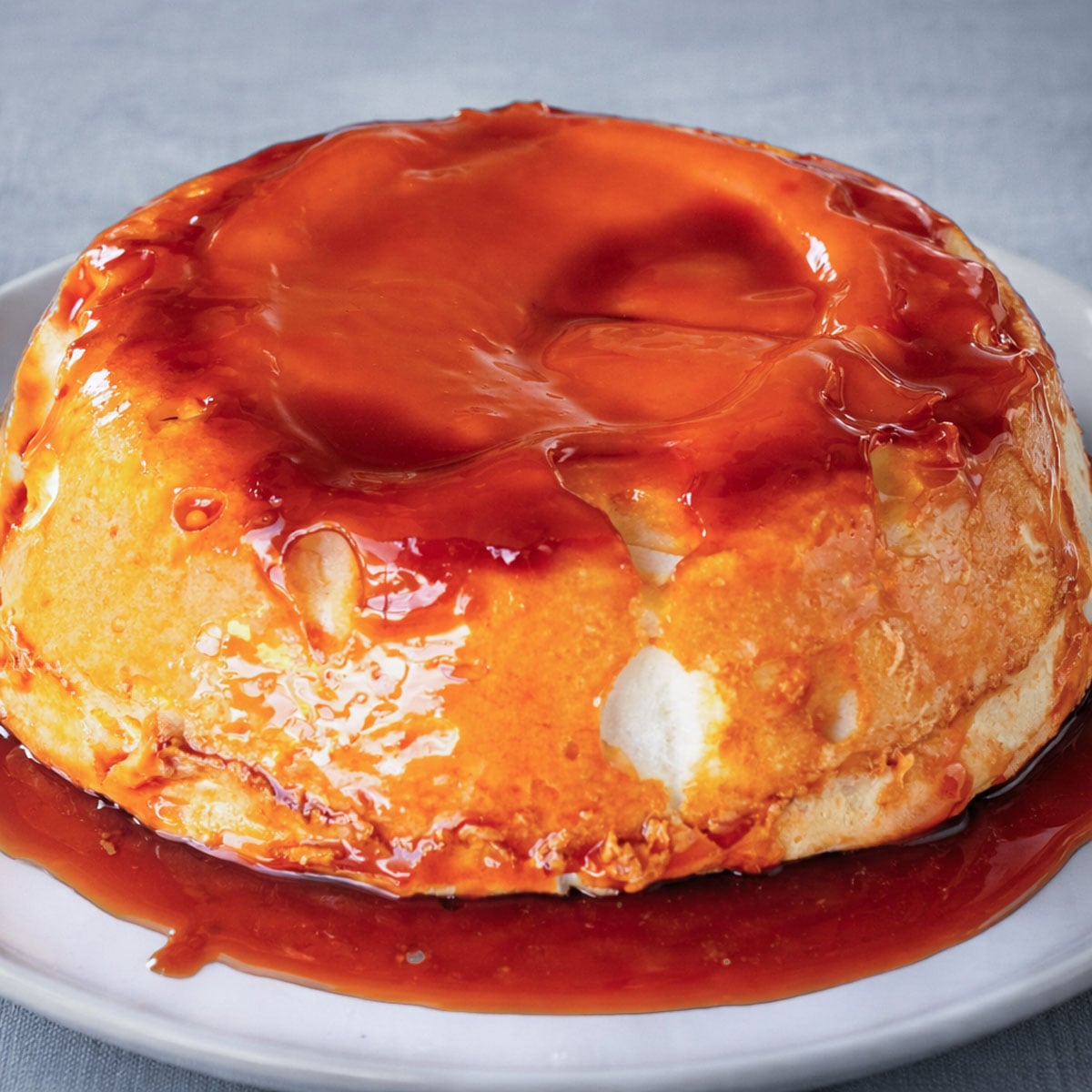 Molotof Cake (Portuguese meringue cake) covered in glossy caramel sauce, being sliced on a plate. 