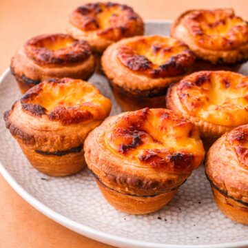 Portuguese egg custard tarts with caramelized tops and flaky pastry on a plate