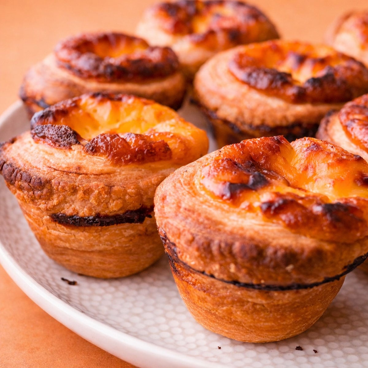 Close-up of Portuguese egg custard tarts with golden flaky layers and caramelized custard tops on a plate