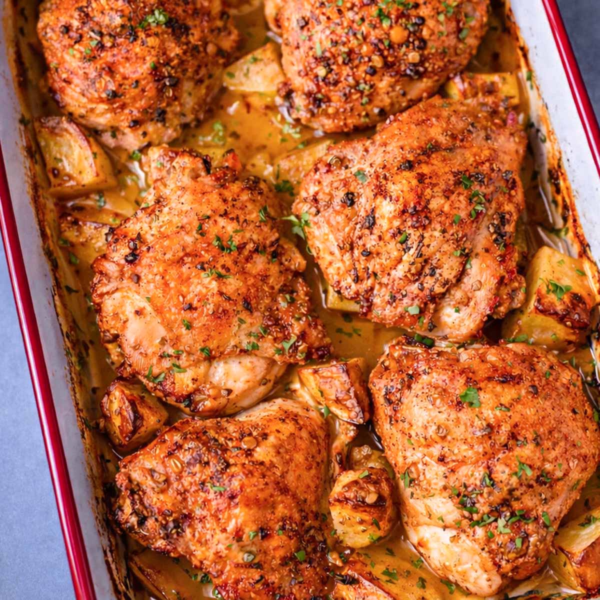 Crispy one pan roasted chicken thighs with potatoes baked together in a roasting dish.