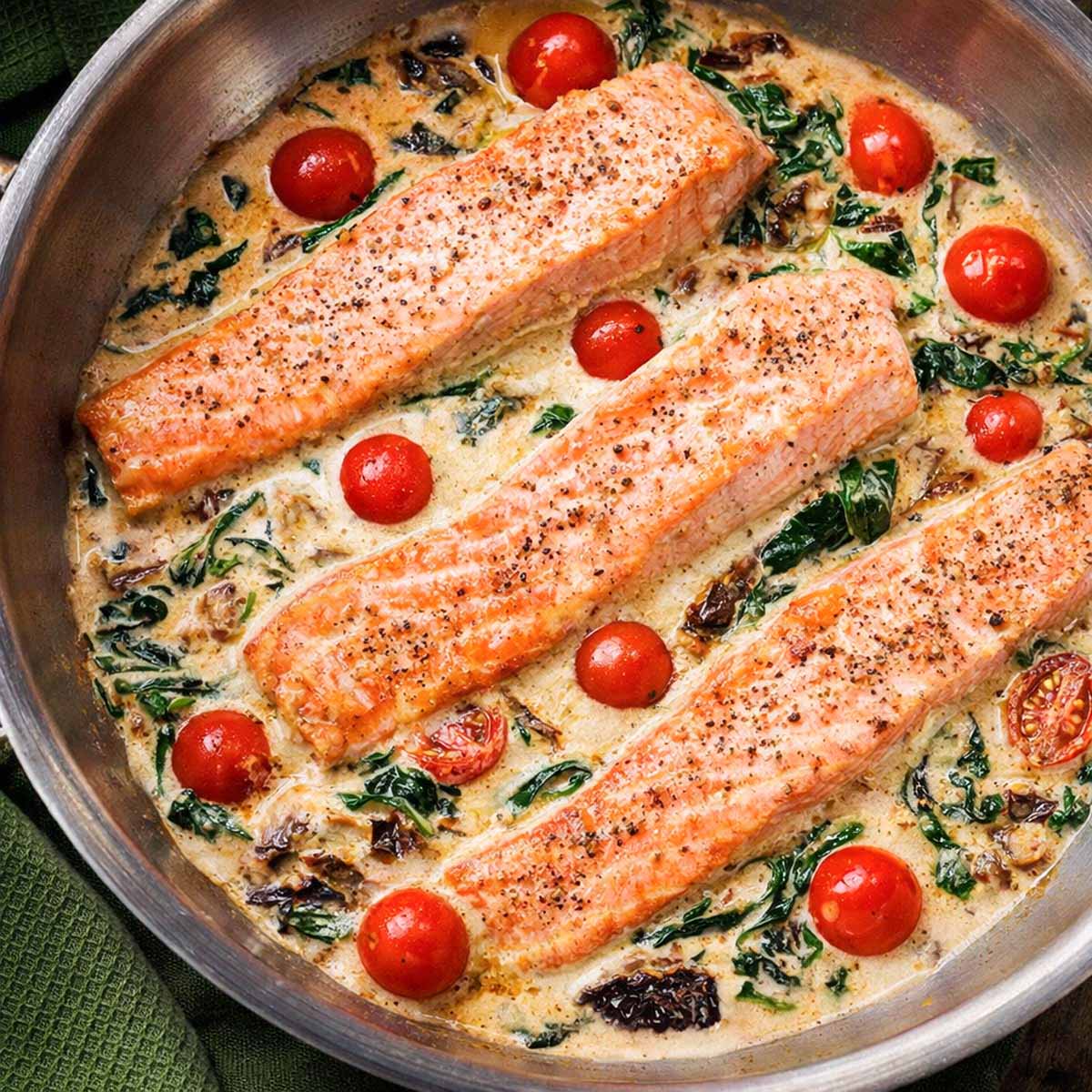 Salmon Florentine cooked in a skillet with creamy spinach sauce, cherry tomatoes, and parmesan. 