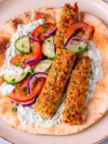 Sheet pan ground chicken kebabs served on warm pita with tzatziki, tomato, cucumber, and red onion.
