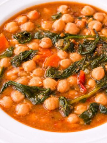 Spanish Chickpea and Spinach Stew (Garbanzos con Espinacas) served in a white bowl with tender chickpeas, wilted spinach, carrots, and a rich tomato-based broth