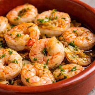 Spanish garlic shrimp gambas al ajillo served in a terracotta dish, with juicy shrimp, golden garlic slices, olive oil, and fresh parsley garnish