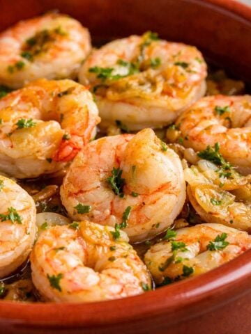 Spanish garlic shrimp gambas al ajillo served in a terracotta dish, with juicy shrimp, golden garlic slices, olive oil, and fresh parsley garnish