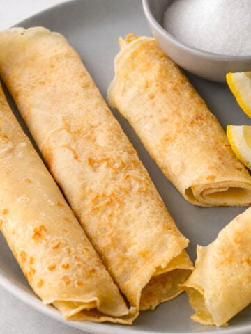 Traditional British pancakes with lemon wedges and sugar, thin golden pancakes rolled and served on a plate