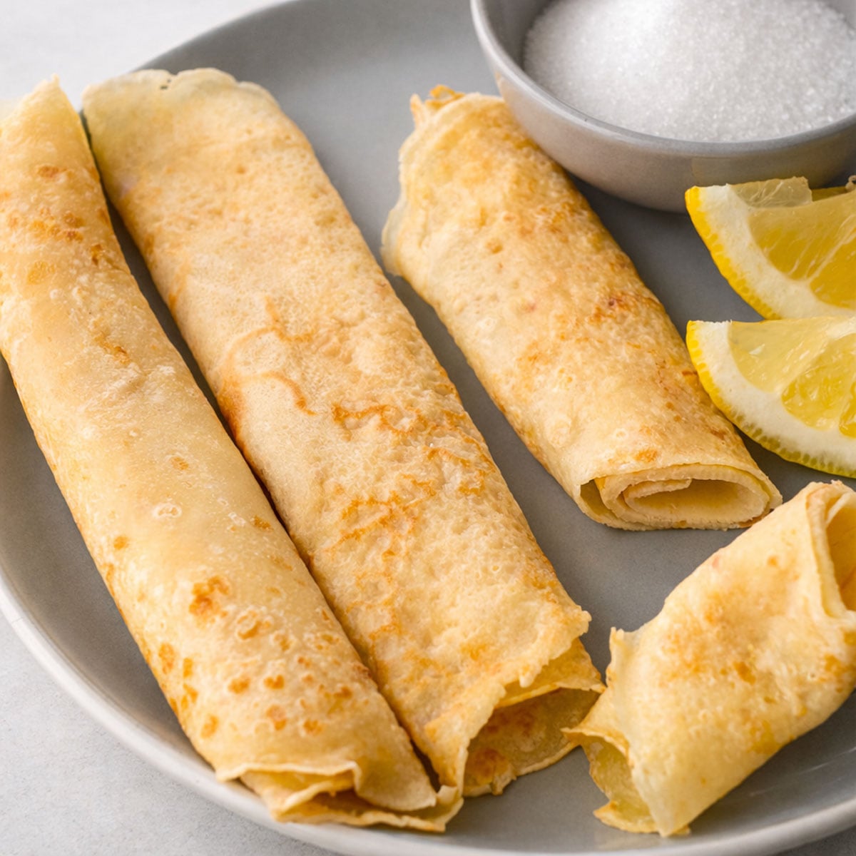 Traditional British pancakes with lemon wedges and sugar, thin golden pancakes rolled and served on a plate