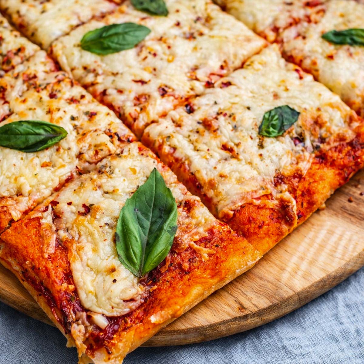 Close-up of vegan Margherita pizza with basil, tomato sauce, and melted vegan cheese on a crispy crust