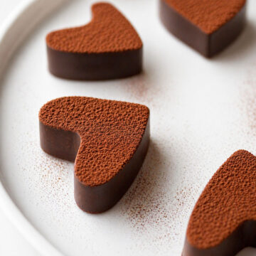 2 Ingredient Chocolate Fudge with Cocoa Powder cut into heart shapes, coated in cocoa and arranged on a white plate