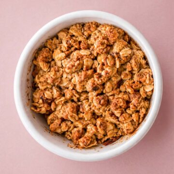 apple crisp with oat topping in a white ramekin, golden brown crumble photographed top view