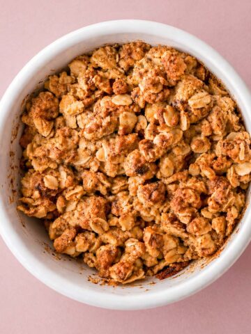 apple crisp with oat topping in a white ramekin, golden brown crumble photographed top view