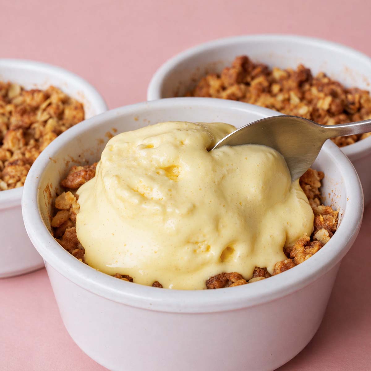 apple crisp with oat topping served in a white ramekin with creamy ice cream and spoon, golden brown oat topping