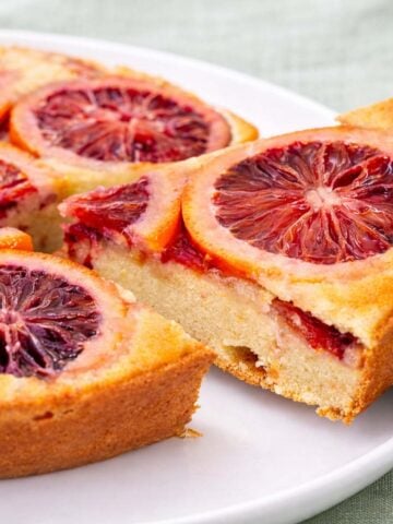 Blood orange upside down cake with caramelized citrus slices, a golden crumb, and a cut slice served on a white plate.