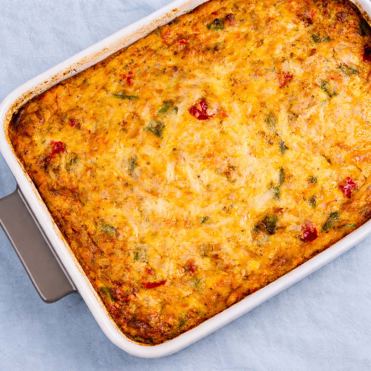 Easy breakfast casserole with ground pork baked with eggs, cheese, peppers, and ground  in a pork baking dish with a golden cheesy top