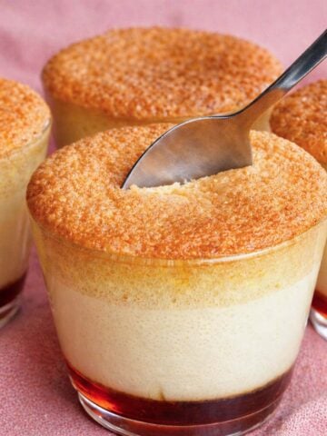 castella pudding cake cups with caramel custard base and sponge top, spoon breaking the golden crust