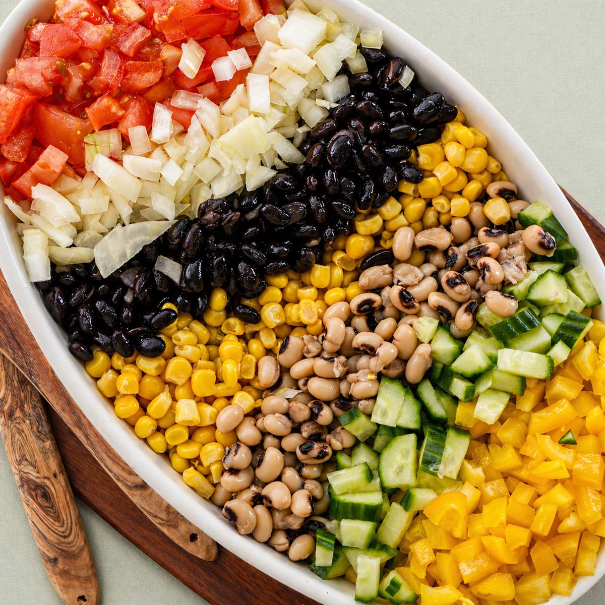 cowboy caviar with black beans corn black eyed peas cucumber tomatoes and onion arranged in a bowl