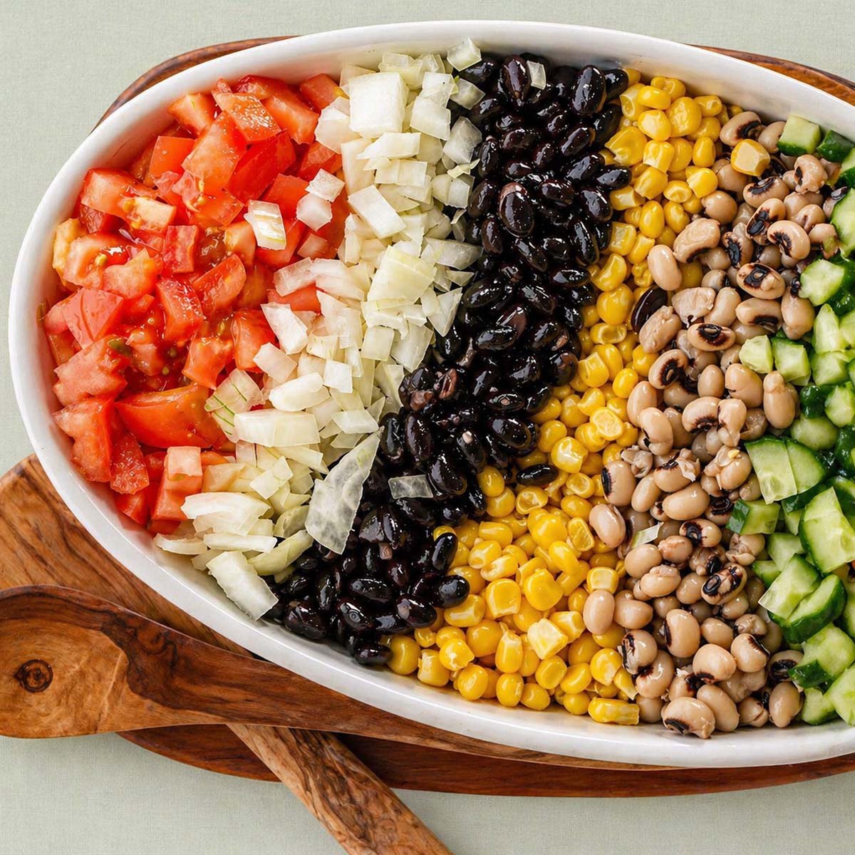 cowboy caviar with tomatoes onion black beans corn black eyed peas cucumber and yellow pepper in a white dish