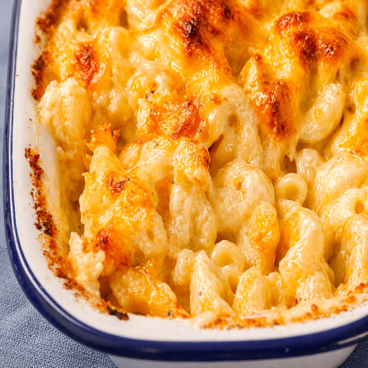 close-up of creamy baked mac and cheese with golden melted cheese in a white casserole dish