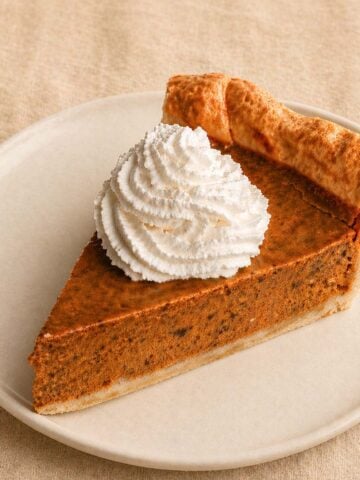 Easy pumpkin pie with condensed milk slice topped with whipped cream on a white plate