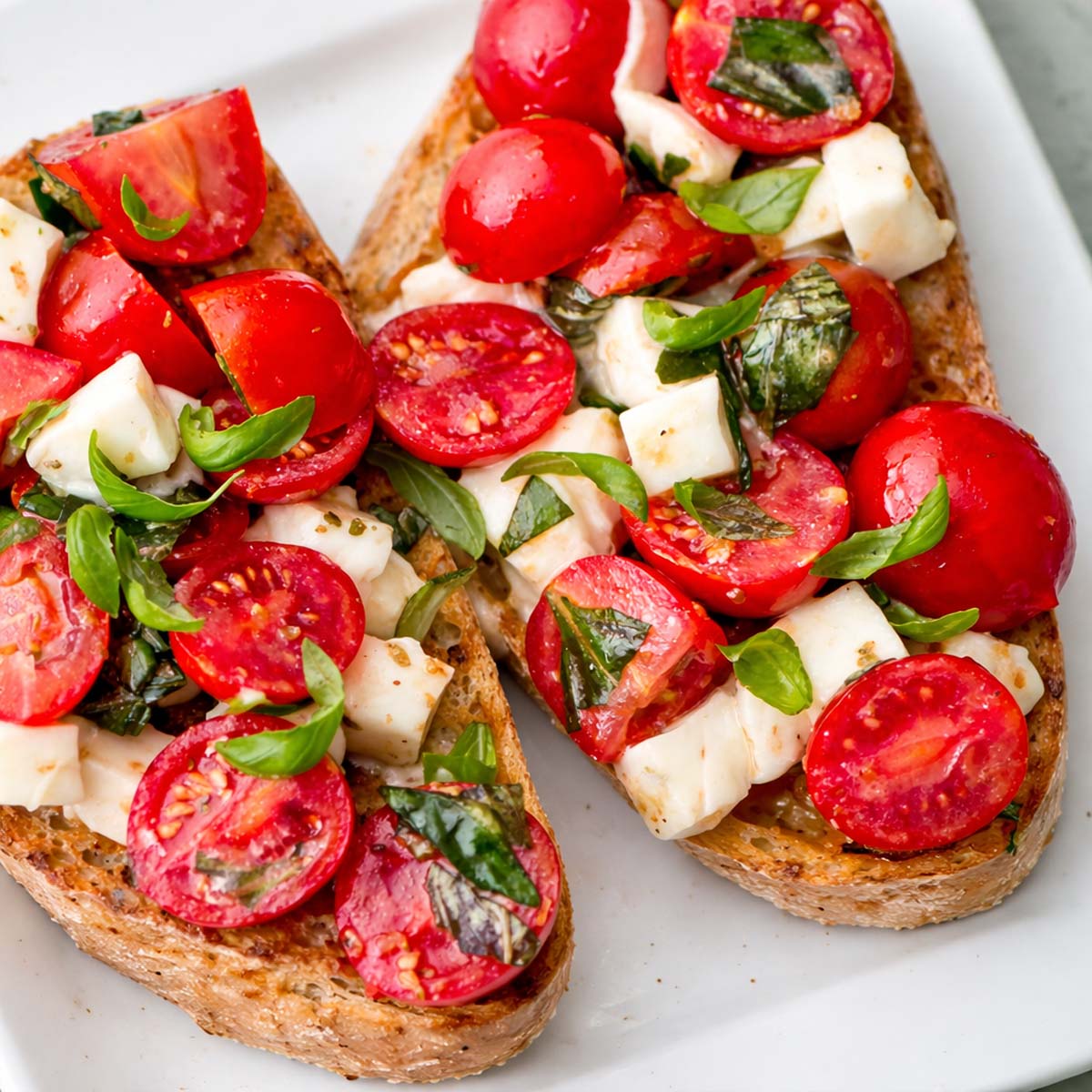 Cherry tomato bruschetta with mozzarella, basil, and olive oil on toasted bread.