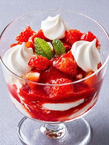 Strawberry Eton mess dessert layered with whipped cream, meringue, and fresh strawberries in a glass coupe