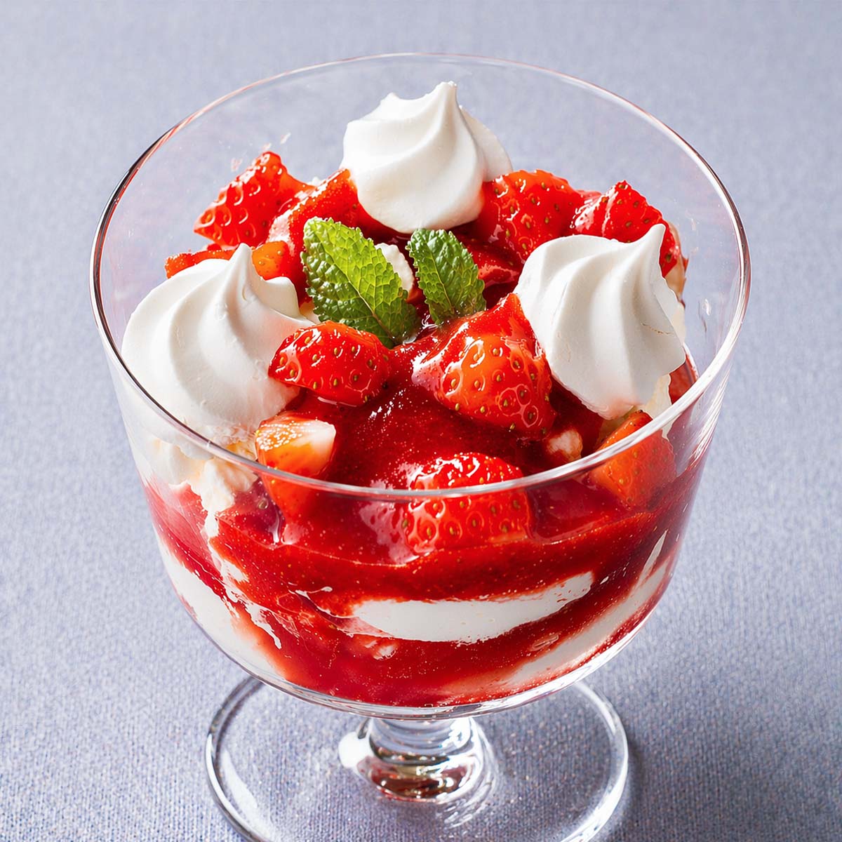 Strawberry Eton mess dessert layered with whipped cream, meringue, and fresh strawberries in a glass coupe