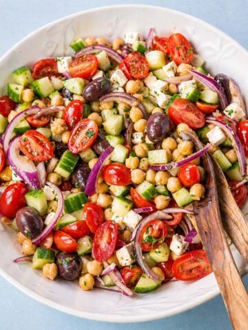 Greek chickpea salad with feta, cucumber, cherry tomatoes, red onion, and olives in a bowl