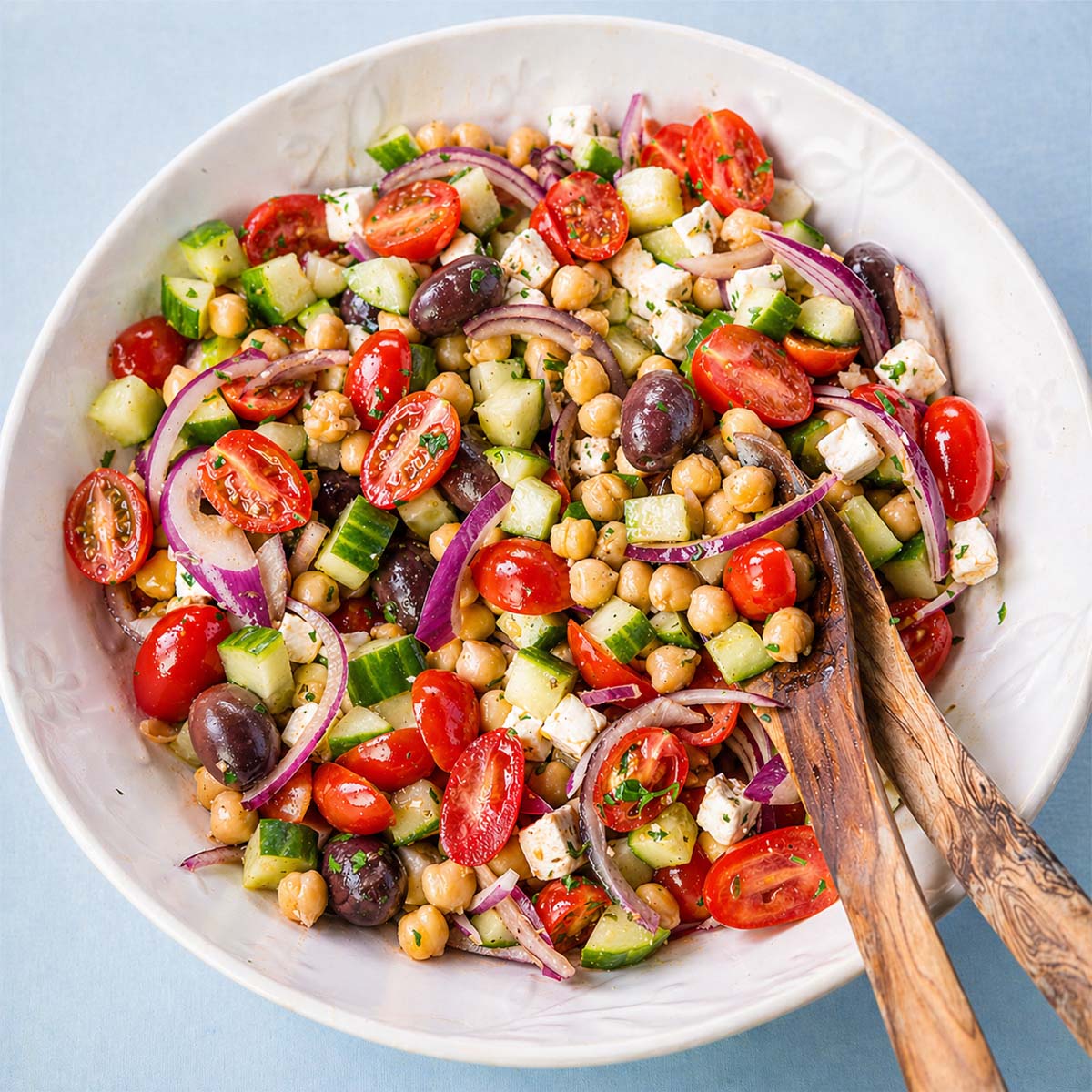 Greek chickpea salad with feta, cucumber, cherry tomatoes, red onion, and olives in a bowl