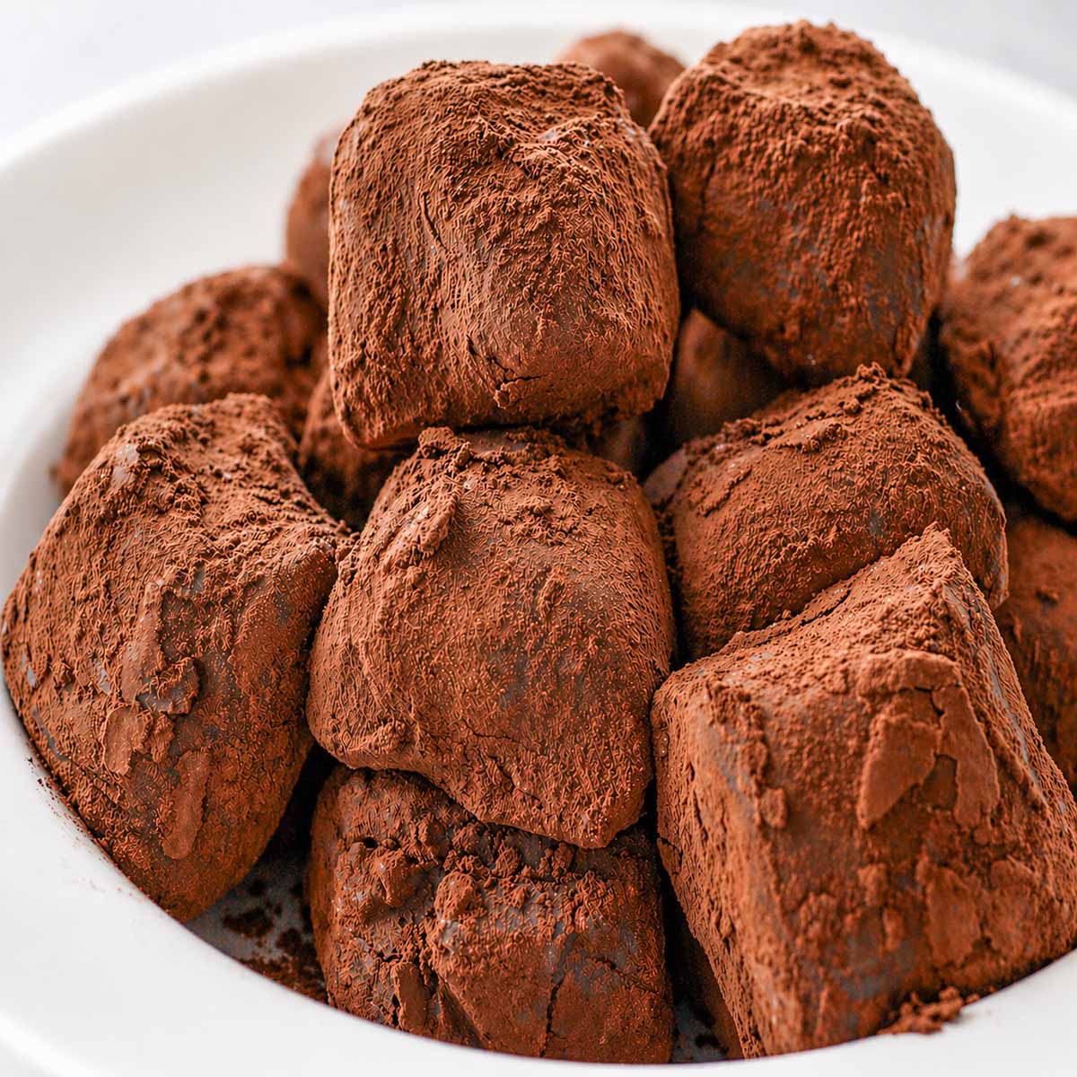 Homemade Chocolate Candy with Cocoa Powder piled in a white bowl, coated in cocoa with a soft, rich and slightly crumbly texture